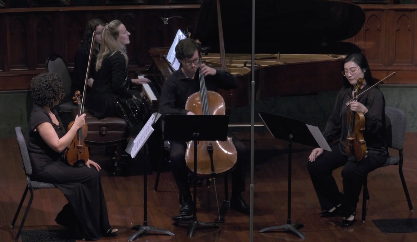 A chamber ensemble — piano, cello, violin, and viola — performing on stage