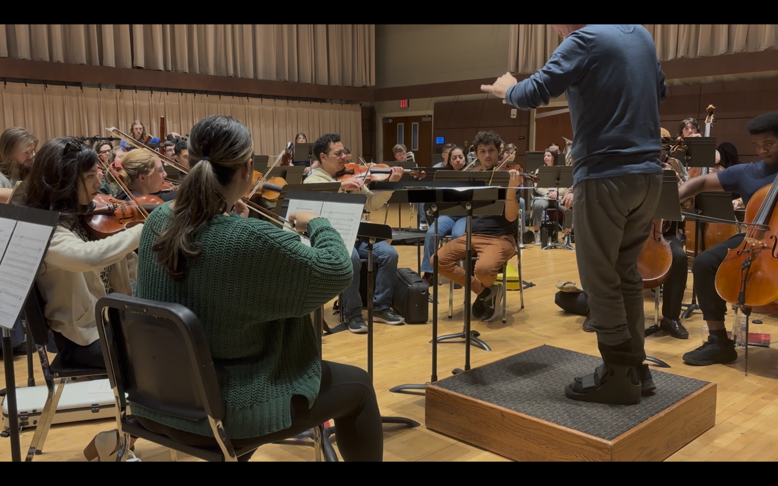 An orchestra in rehearsal with a conductor